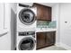 This laundry room features a washer and dryer with modern cabinetry and tile backsplash at 125 Belleview Boulevard # 203, Belleair, FL 33756