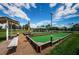 Outdoor bocce ball court with a manicured green surface, wooden borders, shaded seating, and a clubhouse nearby at 1338 Winding Willow Dr, Trinity, FL 34655