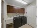 Well-equipped laundry room with dark wood cabinets, utility sink, and modern washer and dryer at 1338 Winding Willow Dr, Trinity, FL 34655