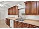 Well-lit kitchen featuring wood cabinetry, tan countertops, and a double stainless steel sink at 13795 Antigua Dr, Seminole, FL 33776