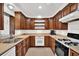 Functional kitchen with wood cabinets, tile countertops, stainless steel sink, and a gas range at 13795 Antigua Dr, Seminole, FL 33776