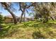 Large backyard with mature trees and pool enclosure, offering ample space and privacy at 14228 Teasdale Ave, Hudson, FL 34667