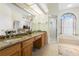 Bright bathroom features a dual sink vanity with granite counters, soaking tub, and walk-in shower at 14228 Teasdale Ave, Hudson, FL 34667