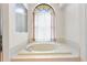 Bright bathroom features an arched window with sheer curtains over the soaking tub at 14228 Teasdale Ave, Hudson, FL 34667