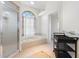 Clean bathroom with soaking tub under an arched window, walk-in shower, and convenient storage shelf at 14228 Teasdale Ave, Hudson, FL 34667