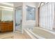Bright bathroom featuring a soaking tub, shower, arched window with curtains, and tiled floor at 14228 Teasdale Ave, Hudson, FL 34667