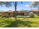 The house featuring a pool enclosure, and set in a lush yard with mature trees at 14228 Teasdale Ave, Hudson, FL 34667