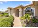 Inviting front entrance with brick pathway, arched portico, manicured bushes and trees at 14228 Teasdale Ave, Hudson, FL 34667