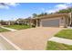 Inviting single-story home with a well-kept lawn, arched windows, and a brick-paved driveway leading to the garage at 14228 Teasdale Ave, Hudson, FL 34667