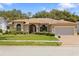 Charming single-story home featuring a well-manicured lawn, arched windows and a brick-paved driveway at 14228 Teasdale Ave, Hudson, FL 34667