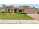 Well-maintained single-story home with a two-car garage, lush landscaping, and a brick-paved driveway at 14228 Teasdale Ave, Hudson, FL 34667