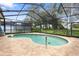 Backyard pool with screened enclosure surrounded by lush landscaping and pavers at 14228 Teasdale Ave, Hudson, FL 34667