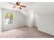Bright bedroom features a ceiling fan, neutral carpet, and a window view of the surrounding neighborhood at 17342 Lawn Orchid Loop, Land O Lakes, FL 34638