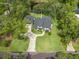 Aerial view of a modern farmhouse home with a lush green lawn, detached garage, and mature trees at 18202 Abbey Ln, Lutz, FL 33548