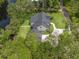 Stunning aerial view of waterfront home with lush landscaping, circular driveway, and dark metal roof at 18202 Abbey Ln, Lutz, FL 33548