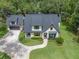 Aerial view of a modern farmhouse home with a gray roof, lush lawn, and a detached garage at 18202 Abbey Ln, Lutz, FL 33548