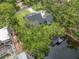 Aerial capture of house with waterway views, set amongst lush trees, showcasing scenic surroundings and dock at 18202 Abbey Ln, Lutz, FL 33548