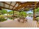 Covered wooden dock features a dining table with benches, perfect for outdoor entertaining and waterfront views at 18202 Abbey Ln, Lutz, FL 33548