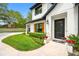 Elegant home entrance featuring a beautifully landscaped yard, black framed windows, and a decorative front door at 18202 Abbey Ln, Lutz, FL 33548