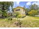 A view of the side yard reveals a two-story home with lush trees and landscaping under a sunny, partly cloudy sky at 214 W Hanna Ave # A, Tampa, FL 33604