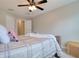 Bright bedroom with ceiling fan, grey-and-white bedspread, pillows, and wood nightstand at 2487 Golden Pasture Cir, Clearwater, FL 33764