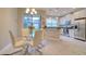 Dining area with a glass table, white chairs, and a view of the modern kitchen at 2487 Golden Pasture Cir, Clearwater, FL 33764