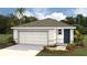 Charming one-story home with a one car garage, landscaped front yard, and a welcoming dark blue front door at 3070 Pink Gerbera Sq, Plant City, FL 33566