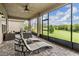 Cozy screened-in patio with lounge chairs, a ceiling fan, and a view of the serene landscape at 3197 Acacia Bay Ave, Wesley Chapel, FL 33543