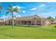 Expansive backyard featuring a screened lanai and well-maintained lawn with mature palm tree at 3337 Crescent Oaks Blvd, Tarpon Springs, FL 34688