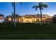 Backyard view of home with enclosed pool at dusk and lush green lawn at 3337 Crescent Oaks Blvd, Tarpon Springs, FL 34688