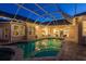Backyard view of enclosed pool at dusk with patio seating and lighting at 3337 Crescent Oaks Blvd, Tarpon Springs, FL 34688