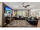 Spacious living room with dark leather furniture, tray ceilings, and a large television at 3532 Wicket Field Rd, Lutz, FL 33548
