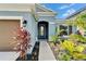 Inviting home entrance features a decorative glass door, sconce, and vibrant landscaping at 5415 Limelight Dr, Apollo Beach, FL 33572