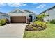 Inviting single-story home featuring a well-manicured lawn and a charming, warm-toned garage door at 5415 Limelight Dr, Apollo Beach, FL 33572