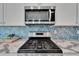Modern kitchen boasts stainless steel appliances, gas range, beautiful blue tile backsplash, and white cabinetry at 5415 Limelight Dr, Apollo Beach, FL 33572