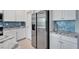Kitchen with stainless steel refrigerator, white cabinetry, granite countertops, and stunning blue tiled backsplash at 5415 Limelight Dr, Apollo Beach, FL 33572