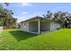 View of backyard showcasing the covered patio, lush green lawn, and perimeter trees at 5707 N 20Th St, Tampa, FL 33610