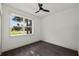 This bedroom features crisp white walls, trim, a window providing natural light, dark wood-style flooring and a ceiling fan at 5709 N 20Th St, Tampa, FL 33610