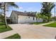 White home featuring an attached garage with a large driveway and tropical landscaping at 5709 N 20Th St, Tampa, FL 33610