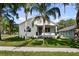 Charming white home with a manicured green lawn, palm trees and inviting front porch with black trim at 5709 N 20Th St, Tampa, FL 33610