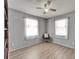 Bedroom features wood-look floors, two windows with curtains, and modern ceiling fan at 6554 34Th N Ave, St Petersburg, FL 33710