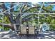 Outdoor dining and lounge area in a screened-in pool area with a lake view at 6561 Exeter Ct, Seminole, FL 33772