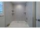 Bright bathroom featuring a soaking tub and stylish white marble tile surround with integrated shelving at 735 123Rd Ave, Treasure Island, FL 33706