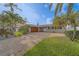Charming single-story home featuring a spacious brick driveway, lush lawn, and mature tropical landscaping at 735 123Rd Ave, Treasure Island, FL 33706