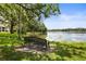 Scenic view of the lake with bench seating, framed by lush trees at 7821 Niagara Ave # 2102, Tampa, FL 33617