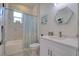 Bright bathroom with marble-look tile, hexagon mirror, and shower with blue patterned curtain at 803 Oak Bend Ln, Dunedin, FL 34698