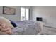 Modern bedroom featuring sleek gray bedding, wood-look flooring, and a sliding glass door leading to a balcony at 803 Oak Bend Ln, Dunedin, FL 34698