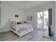 Bright bedroom features gray wood-look floors, white walls, and a sliding glass door leading to a small balcony at 803 Oak Bend Ln, Dunedin, FL 34698