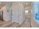 Bright hallway with gray wood floors, white doors, trim, and decor, connects the kitchen to the laundry room and bedroom at 803 Oak Bend Ln, Dunedin, FL 34698
