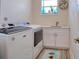 Functional laundry room features modern washer, dryer, sink, white cabinets, and gray wood flooring at 803 Oak Bend Ln, Dunedin, FL 34698